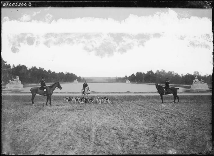 Cavaliers et meute de chiens de chasse devant un bassin