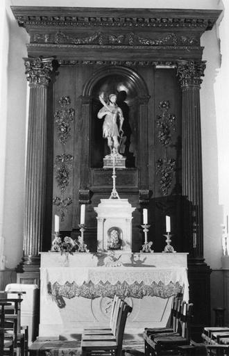 Retable architecturé percé d'une niche centrale, décor sculpté de guirlandes de feuillages et de chutes de fleurs, bois sculpté