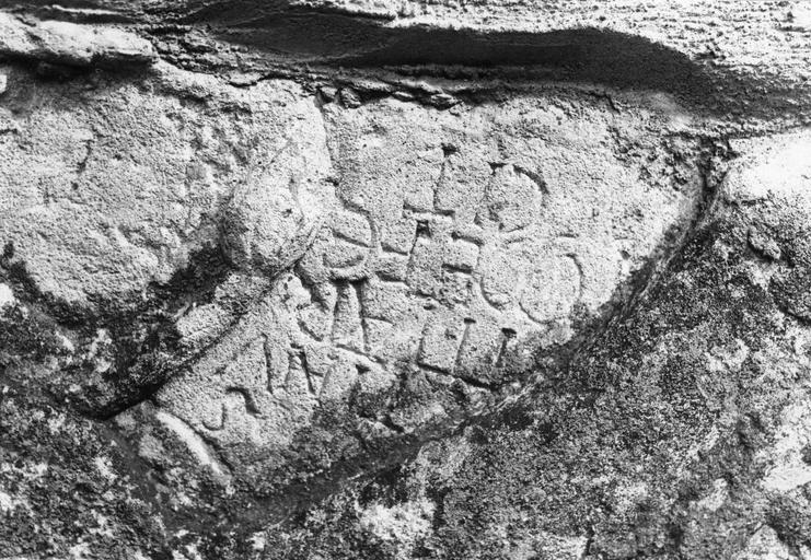 Sculpture : pierre de parement du mur de l'église, détail d'une inscription placée sous le ventre du lion, pierre gravée