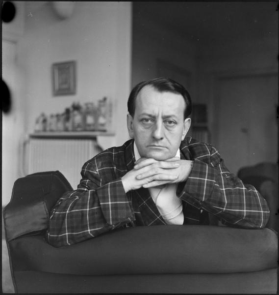 Malraux, les mains jointes sous le menton, appuyé sur un fauteuil