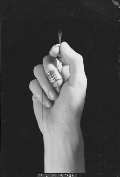 Main avec dé à coudre et aiguille