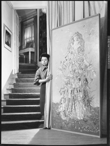 Suzanne Van Damme présentant une toile dans un escalier