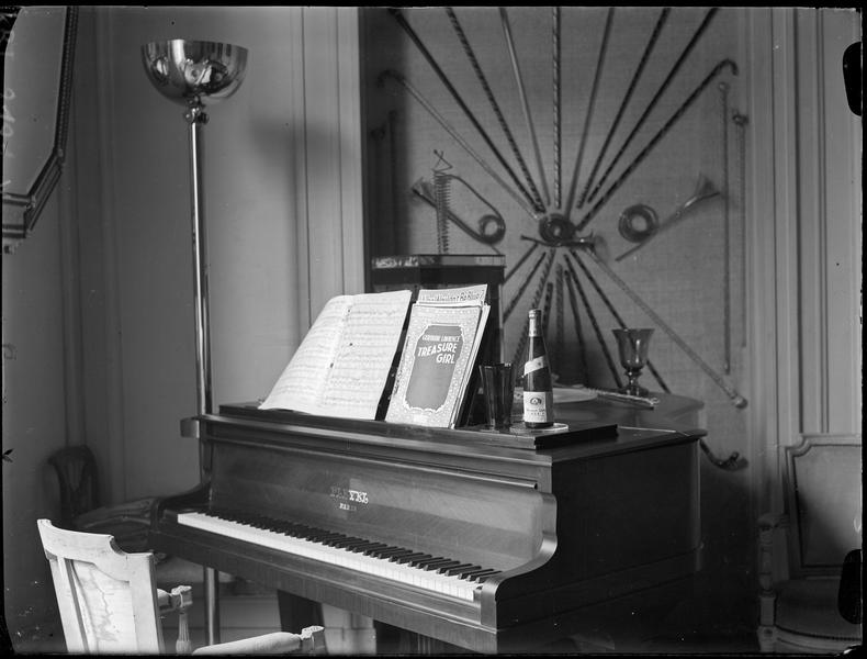 [Publicité pour Clicquot Club Sec : Une bouteille posée sur un piano dans un hôtel]