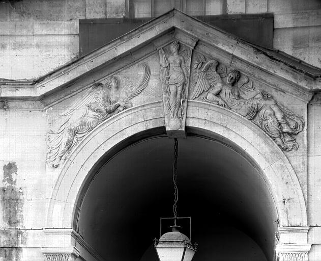 Extérieur, corps central de la façade est : encadrement de la porte cochère et du premier étage, avec des figures ailées sur l'arcature de la porte