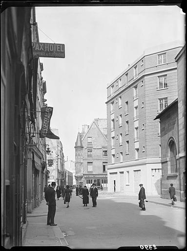 Passants dans la rue, avec l'hôtel Hérouet en arrière-plan