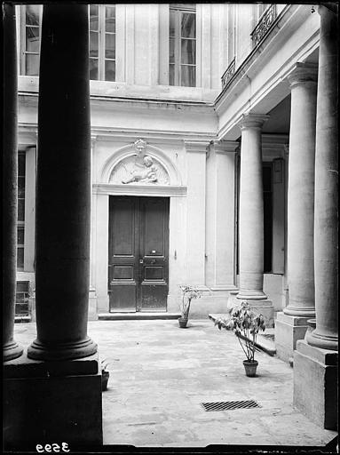 Façade est sur cour. Colonnade et porte surmontée d'un bas-relief représentant un enfant sur un dauphin