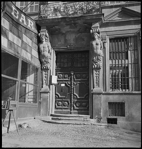 Porte décorée de roses, encadrée par des Atlantes