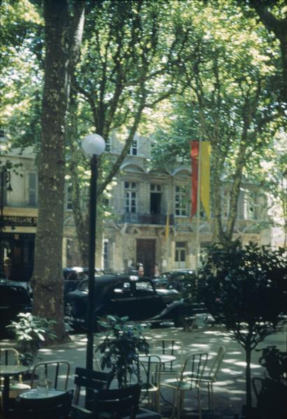 Façade sur la place, terrasse de café et voitures