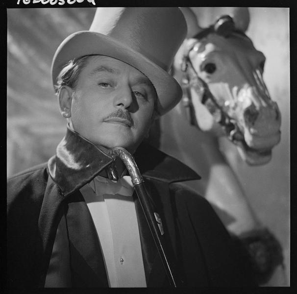 Anton Walbrook en costume et chapeau haut-de-forme, tenant une canne à la main