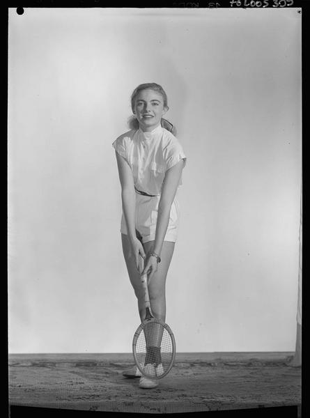 Claudine Sterkers, en pied, portant une tenue de tennis, une raquette dans les mains