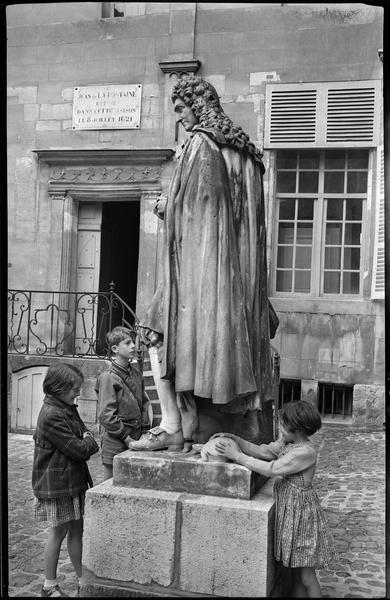 Des enfants au pied de la sculpture représentant le poète