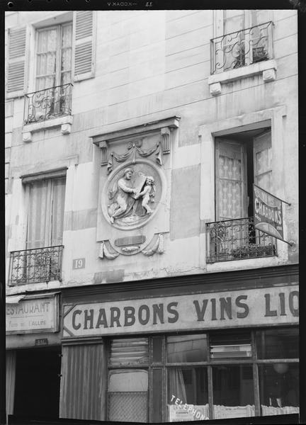 Bas-relief au dessus d'une enseigne d'une boutique de charbon, vins, liqueurs