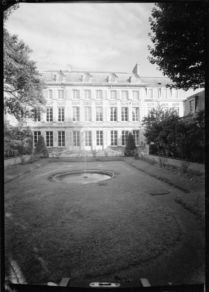 Façade côté jardin avec un bassin circulaire au premier plan