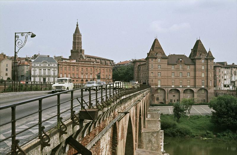 Vue générale de la ville : voitures sur le pont, façades du tribunal de commerce et du musée Ingres, clocher de l'église à l'arrière-plan