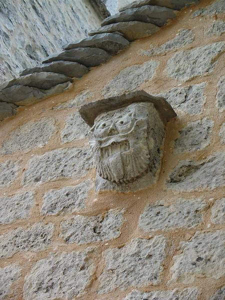 corbeau sculpté situé sur la façade de l'église, représentation d'un visage humain grimaçant