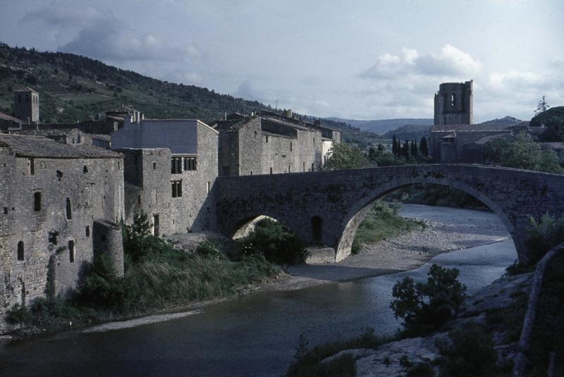 Vue générale du village, clocher de l'église abbatiale et pont romain au premier plan