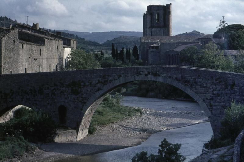 Vue générale du village, clocher de l'église abbatiale et pont romain au premier plan