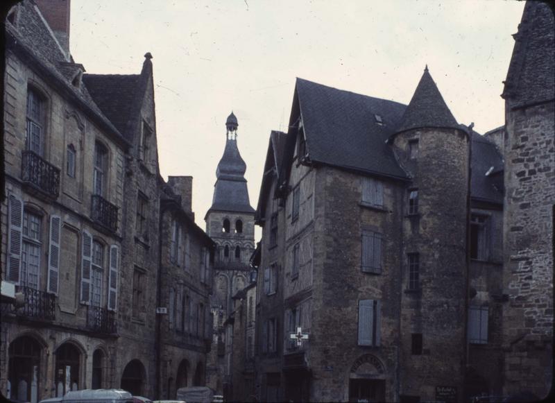 Clocher depuis une rue bordée de maisons anciennes en pierre