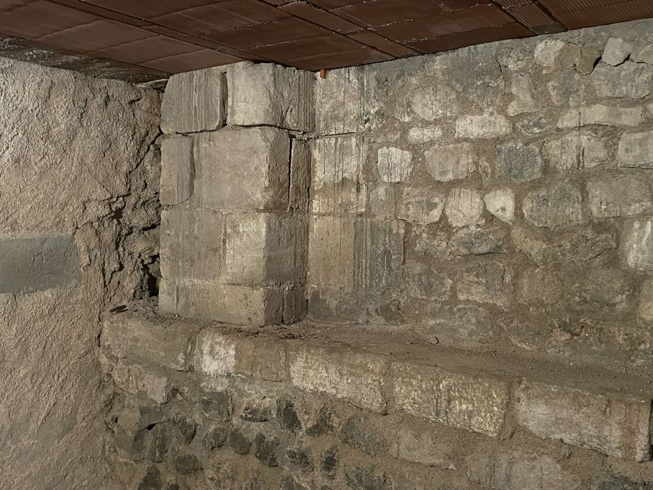 base maçonnée en arkose de la façade romane nord de l'église abbatiale visible depuis une cave voisine