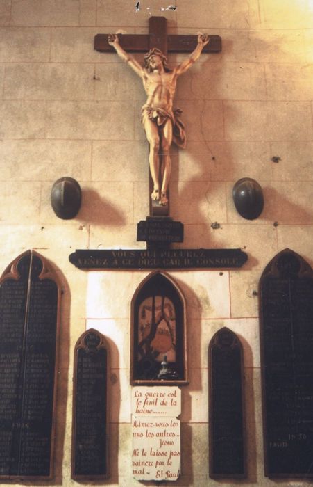 monument commémoratif composé des vestiges de la profanation et de l'incendie du presbytère : statue du Christ en croix, huit panneaux commémoratifs, deux casques, niche avec fragments de la porte du tabernacle et pied d'ostensoir