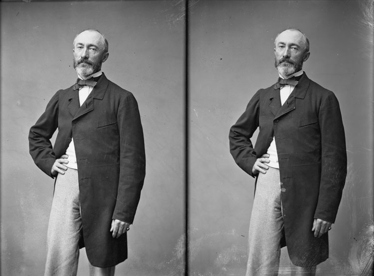 Armand Noël, sculpteur. En mi-corps, une mains posée à la hanche, pose de face.