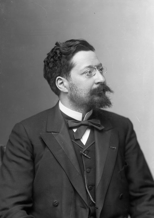 Auguste Burdeau, écrivain et homme politique. En portrait, pose de trois-quart et portant des binocles.