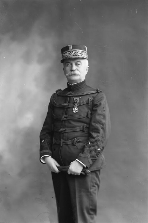 Georges Adolphe Léon Dieudonné, en uniforme militaire de général de brigade en petite tenue de la Troisième République. En mi-corps, pose de face, portant la médaille de la Légion d'Honneur, son képi et tenant dans les mains ses gants.