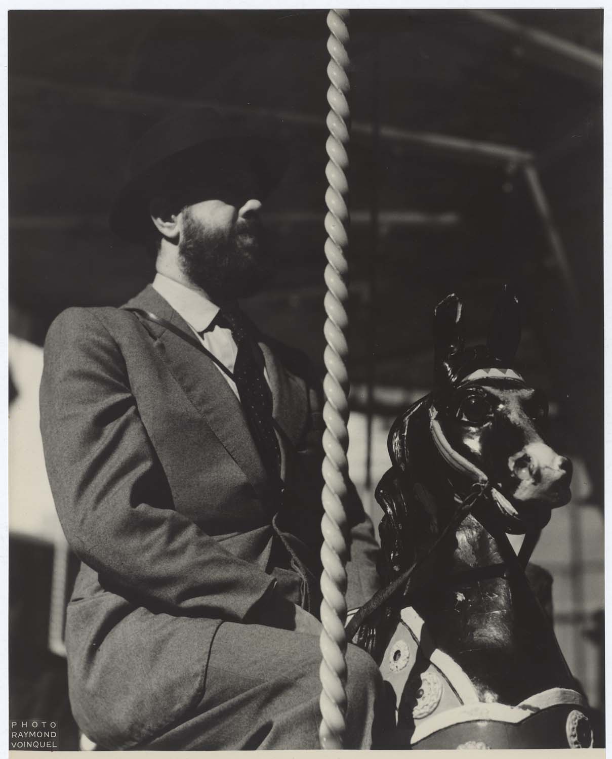 Michel Simon assis sur un cheval de bois, dans un manège