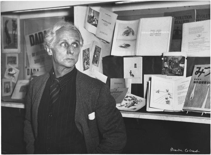 Max Ernst à la Hune, 1950 ; [ Max Ernst debout devant des vitrines consacrées au dadaisme et au surréalisme ]