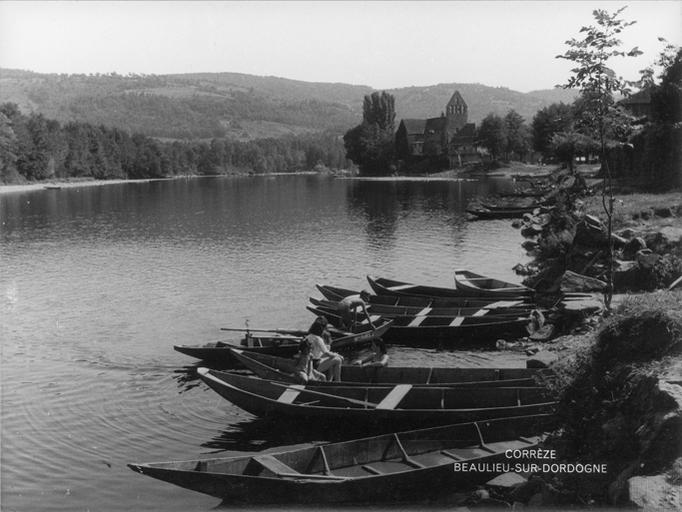 Les rives de la Dordogne, des bateaux avec une femme et des enfants, et la Chapelle des Pénitents en arrière plan