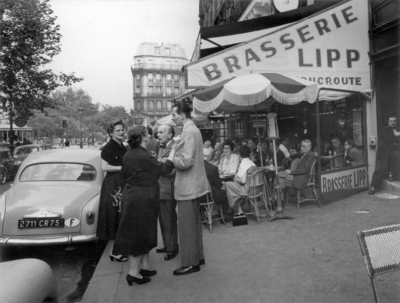 Terrasse animée de la brasserie Lipp et groupe debout en pleine discussion