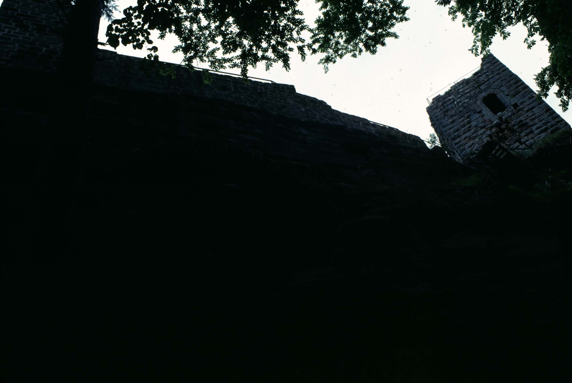 Rocher et vestiges du château face sud, vue en contre-plongée à contre-jour