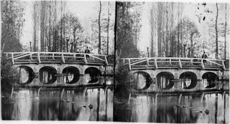 Un couple se tient sur un pont, sur le plan d'eau du château