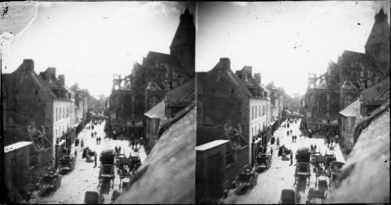 Vue d'une rue animée par des charrettes et l'abside de l'église Saint-Gervais, vue de l'atelier du photographe