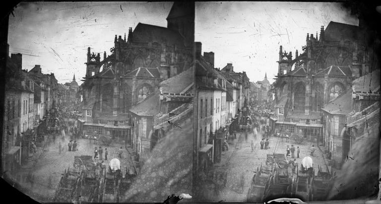 Vue d'une rue animée par des charettes et de l'abside de l'église Saint-Gervais-Saint-Protais