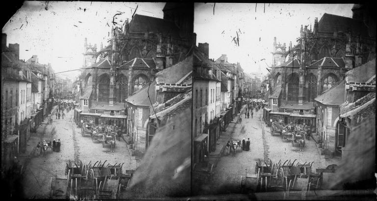 Vue d'une rue animée par des charettes et de l'abside de l'église Saint-Gervais-Saint-Protais, prise de l'atelier du photographe