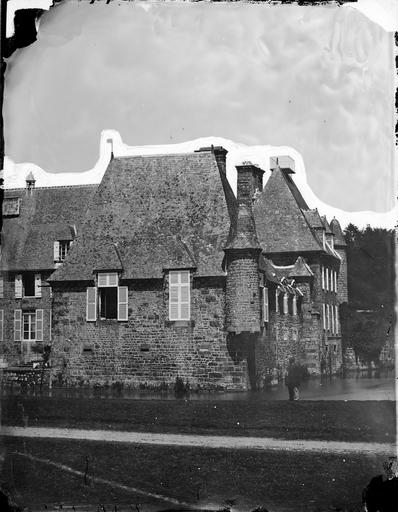 Vue du château entouré de douves, une tourelle à l'angle, un homme posant