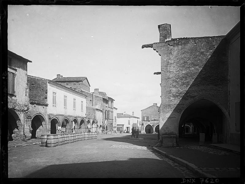 Façades sur la Place du Marché, galerie d'arcades et alignements de tonneaux