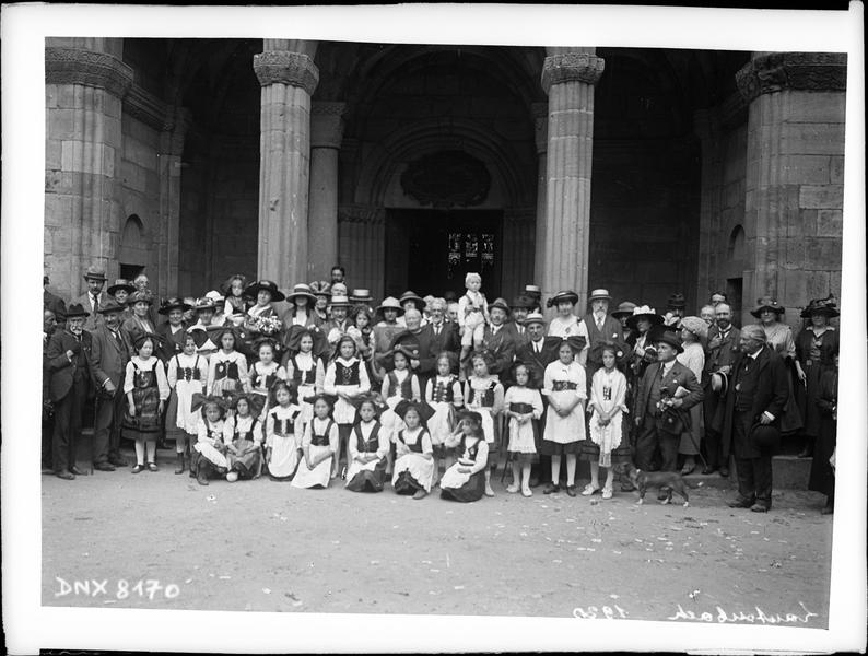 Congrès de 1920, portrait collectif : congressistes et femmes en costume traditionnel alsacien devant le porche de l'église