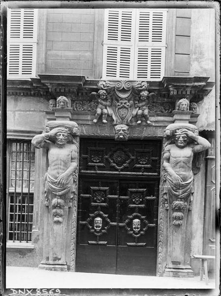 Porte monumentale flanquée d'atlantes et ornée de putti encadrant un blason