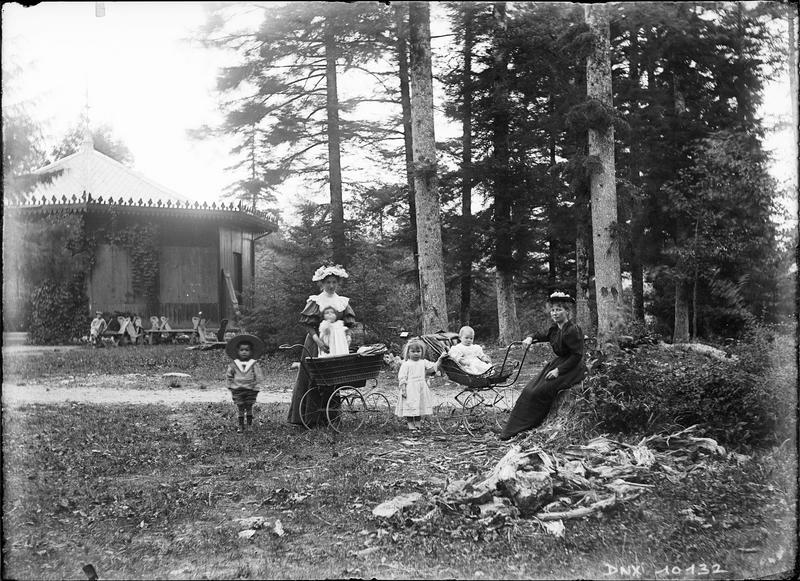 Femmes, enfants et landaus près d'un pavillon forestier