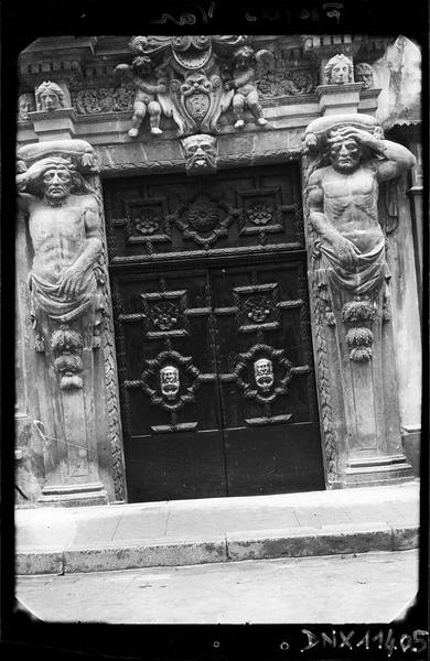 Porte monumentale flanquée d'atlantes et ornée de putti encadrant un blason