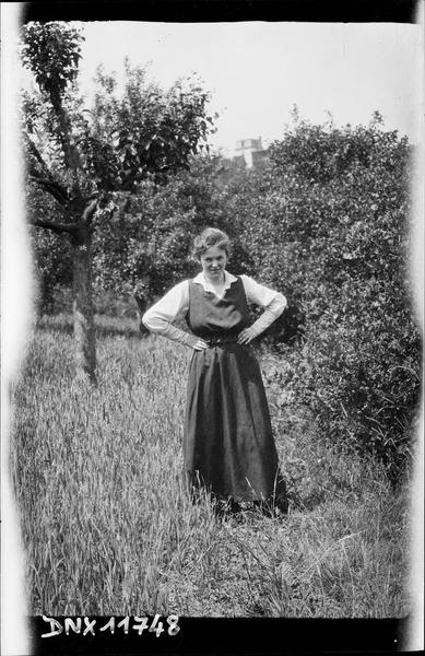 Portrait : jeune femme debout, les mains aux hanches