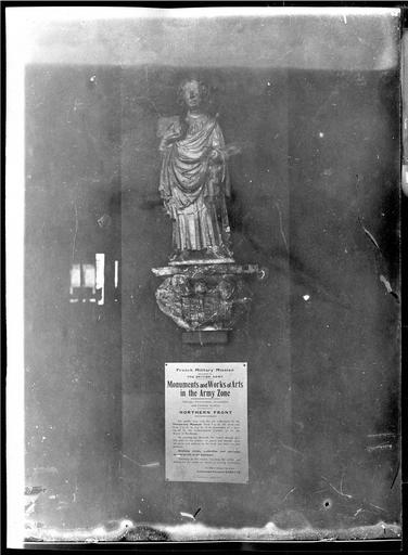 Statue : saint Quentin, en pierre, provenant de la collégiale de Saint-Quentin. Musée provisoire après l'occupation allemande. Affiche anglaise