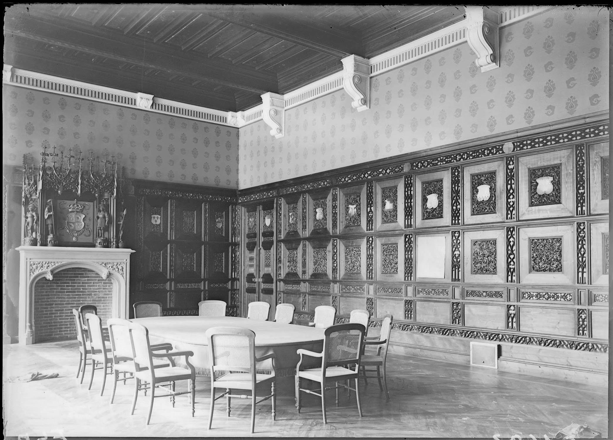 Vue intérieure d'une grande salle avec boiseries et cheminée