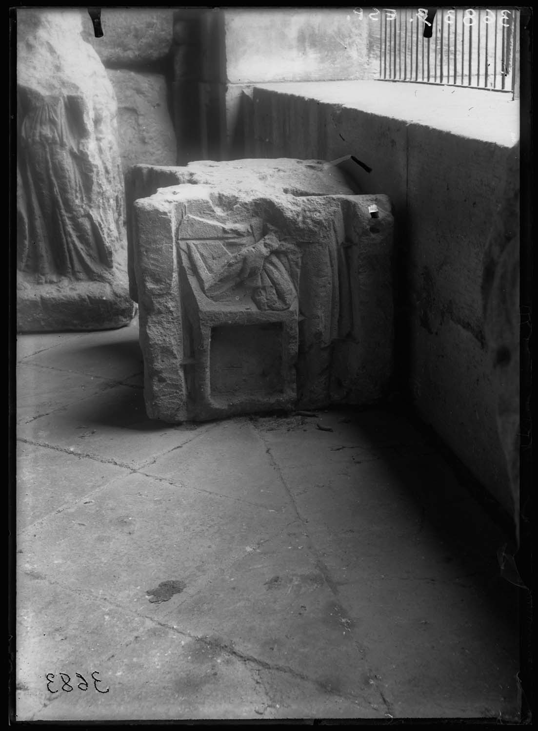 Bloc sculpté avec un personnage tenant une paire de ciseaux et coupant une pièce d'étoffe