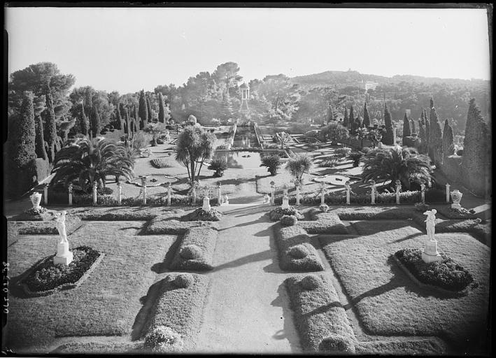 Allée d'un parc, avec le bassin au milieu, en perspective les marches montant vers un belvédère, les parterres de compartiments ornés des statues