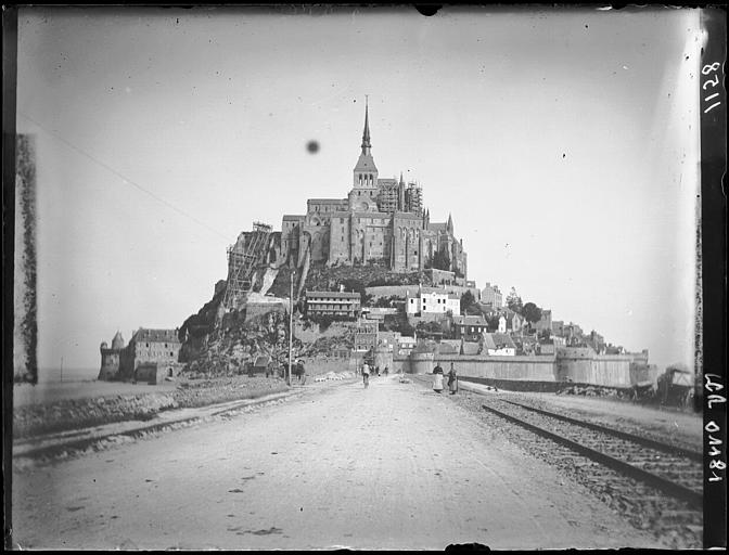 Mont-Saint-Michel avec la route d'accès. Vue d'ensemble. Edifices en restauration. Voie ferrée