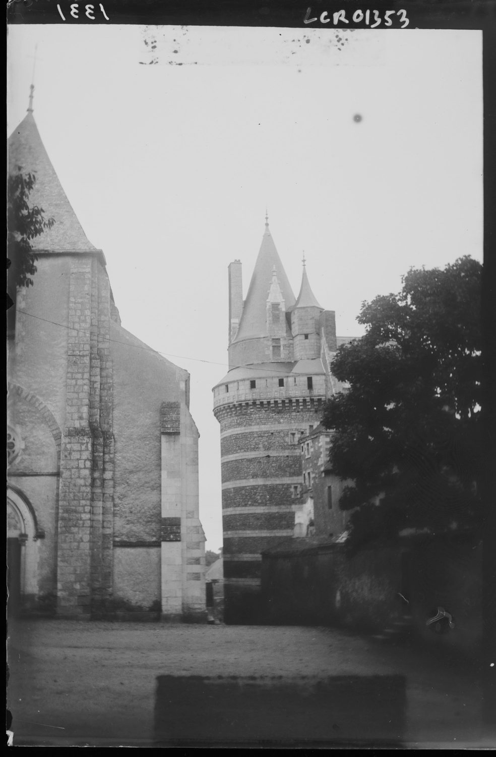 Vue partielle de la façade ouest de l'église. A l'arrière-plan, le donjon du château