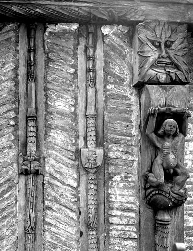 Premier étage, décoration de potelets : homme nu, tête de monstre, blason avec une femme